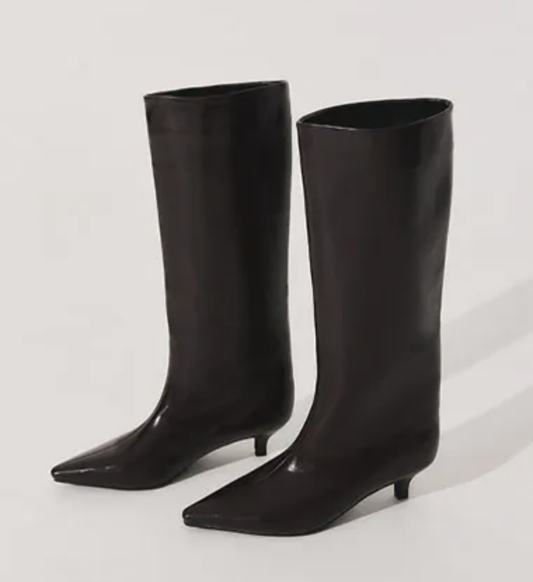 Pair of black knee-high leather boots photographed against a pale neutral background, highlighting their shape and finish.